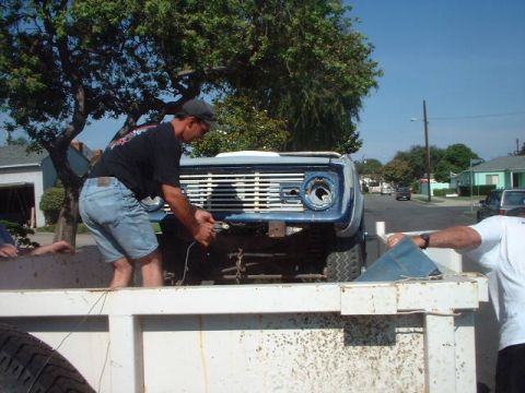 1966 Ford Bronco - A man loads a blue 1966 Ford Bronco into a trailer, its front grille and one headlight missing.