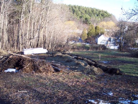2001 Ford Crown Victoria - A white trailer sits on a debris-strewn lot with trees and houses in the background.