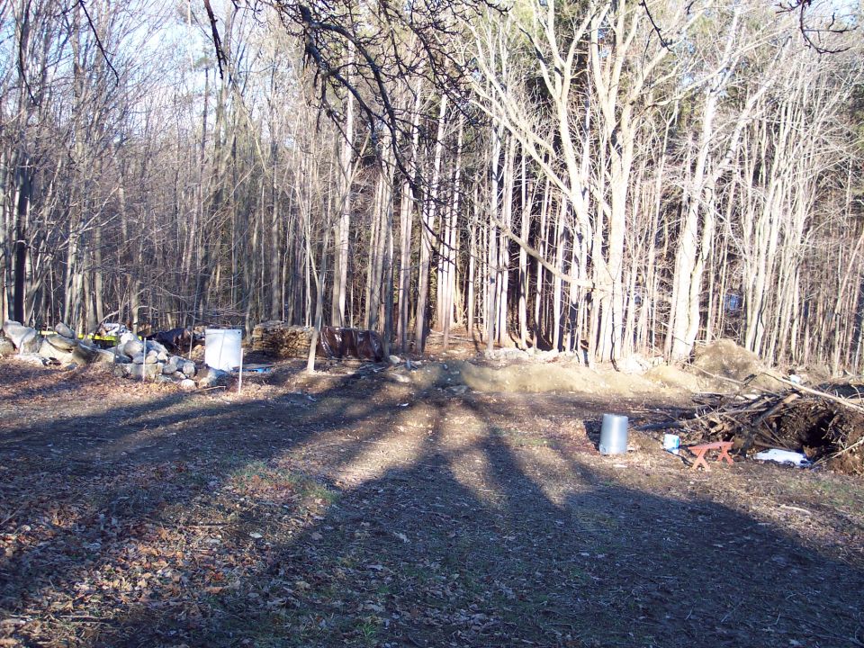 Wooded area with debris and a metal barrel