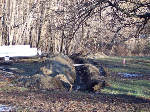 2001 Ford Crown Victoria - A trailer sits near a trench and dirt piles on a grassy area with trees in the background.