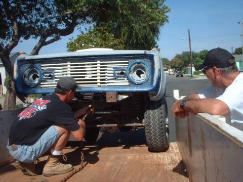 1966 Ford Bronco - A blue 1966 Ford Bronco is secured to a trailer, ready for transport.