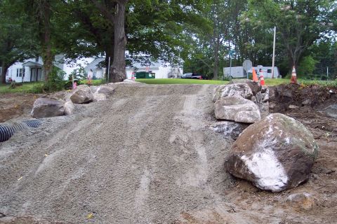 2001 Ford Crown Victoria - A construction scene shows a dirt ramp with large rocks and tire tracks, with houses and trees in the background.