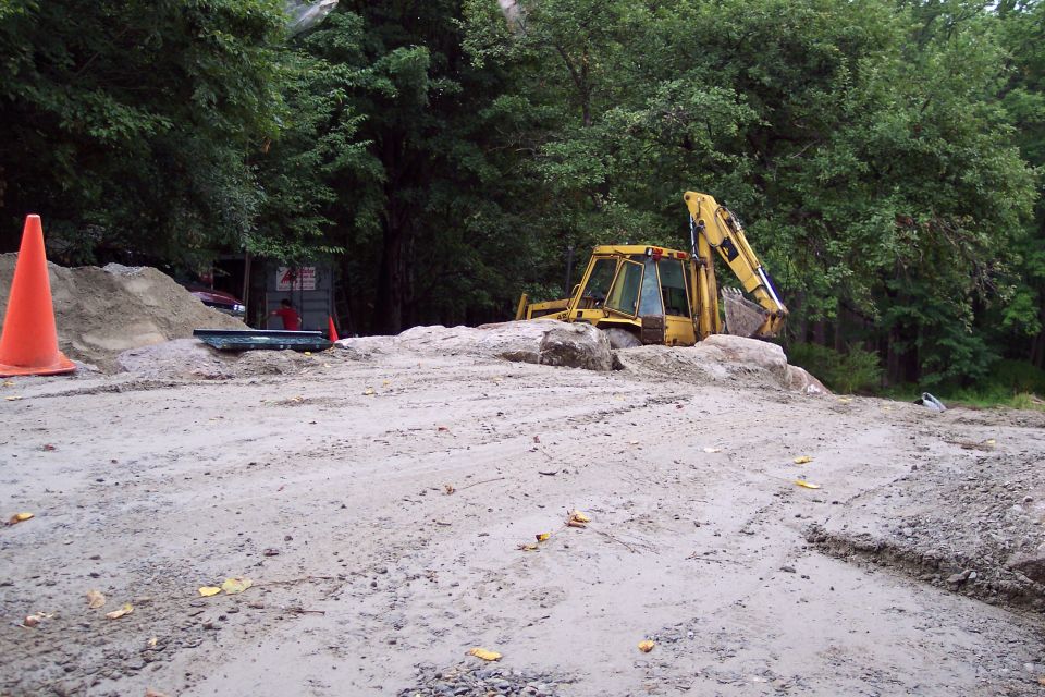Yellow backhoe loader partially buried in dirt pile, construction site