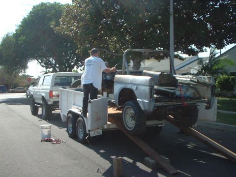 1966 Ford Bronco - A man is loading a disassembled vehicle onto a trailer, with a pickup truck attached.