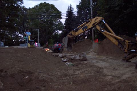 2001 Ford Crown Victoria - Construction scene with an excavator and an ATV amidst dirt piles and trees.
