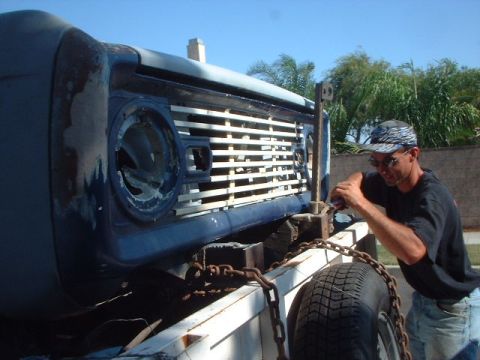1966 Ford Bronco - A man works on the front grille of a 1966 Ford Bronco, which is loaded onto a trailer.
