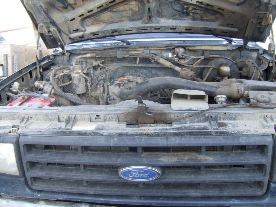Ford truck engine bay with hood open. Grille has Ford logo