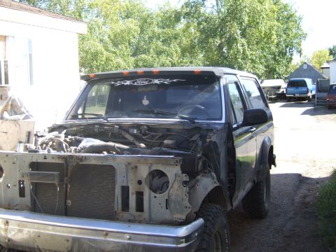 1989 Ford Bronco - 1989 Ford Bronco undergoing front end work, with other vehicles in the background.