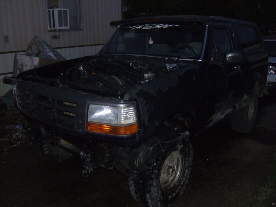 Black Ford Bronco with hood open, parked outside a building