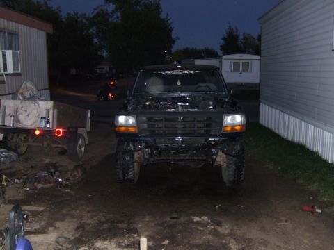 1989 Ford Bronco - A black Ford truck is parked outside with its hood open, showing a modified front end.