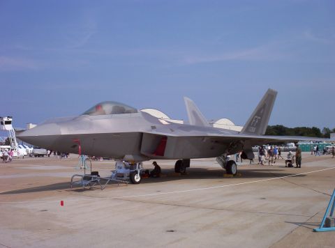 2003 Ford Crown Victoria - An F-22 Raptor fighter jet is parked on the tarmac at an airshow, with spectators nearby.