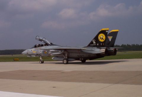 2003 Ford Crown Victoria - A US Navy F-14 Tomcat fighter jet sits on the tarmac with its canopy open, displaying squadron markings on its tail.