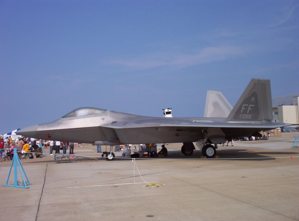 F-22 Raptor fighter jet on display at an airshow, with people around