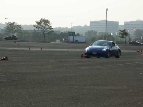 2001 Mercury Grand Marquis - A blue sports car navigates a course marked by orange cones in an open lot.
