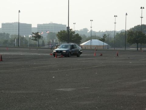2001 Mercury Grand Marquis - A dark sedan drives through a course marked by orange cones on a paved lot.