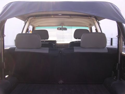 1985 Toyota 4Runner - Rear view of the interior of a 1985 Toyota 4Runner, showing the back seats and the soft top.