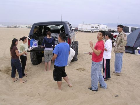 1985 Toyota 4Runner - A group of friends are having a gathering on the beach next to a modified SUV.