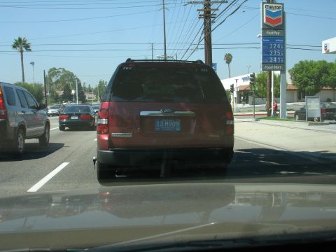 1993 Ford Taurus - Rear view of a red Ford Explorer SUV driving on a sunny day.