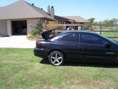 1998 Dodge Avenger - Black 1998 Dodge Avenger coupe with its trunk open, parked on a grassy lawn near a residential garage.