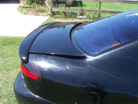 1998 Dodge Avenger - Aftermarket rear spoiler installed on a dark-colored car's trunk.