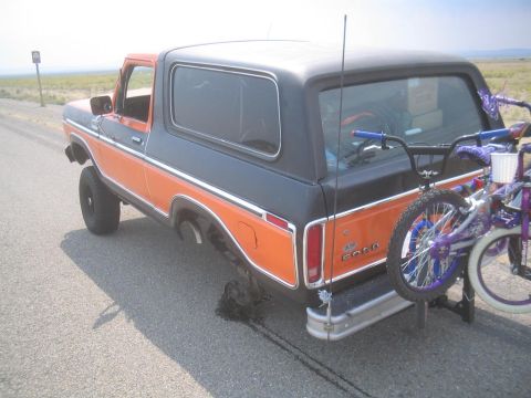 1979 Ford Bronco - A two-tone Ford Bronco is parked on the roadside, carrying two bicycles on a rear-mounted rack.