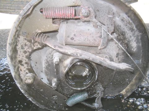 1979 Ford Bronco - Close-up view of a vehicle's brake drum assembly, showing signs of wear and fluid leakage.