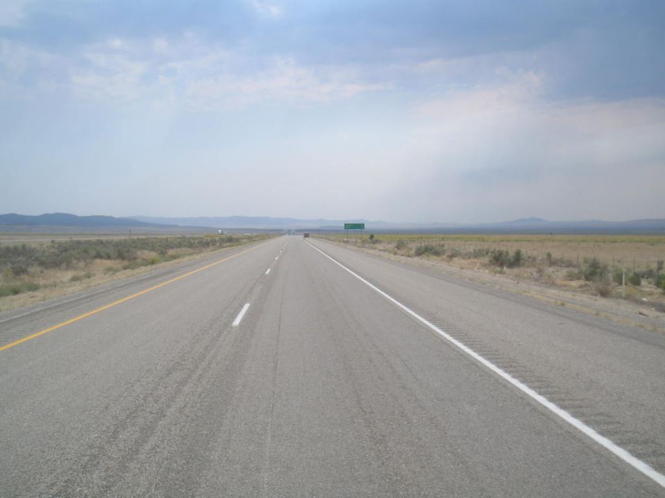 Open highway stretches towards distant mountains under a cloudy sky