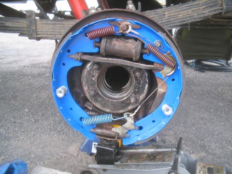 1979 Ford Bronco - Close-up view of a vehicle's brake drum assembly, showing new blue brake shoes and various springs.