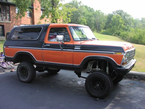 1979 Ford Bronco - Modified 1978 Ford Bronco with custom exhaust and lifted suspension sits parked on asphalt.