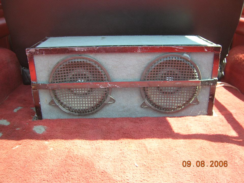 Custom dual speaker enclosure with red trim and metal grilles, sitting on red carpet