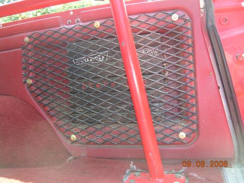 1985 Ford Bronco - Interior view of a vehicle's red panel with a speaker behind a protective grille and a red roll bar.