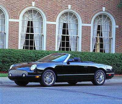 2002 Ford Thunderbird - This black 2002 Ford Thunderbird convertible is shown from a three-quarter front view, parked in front of a brick building with arched wind…