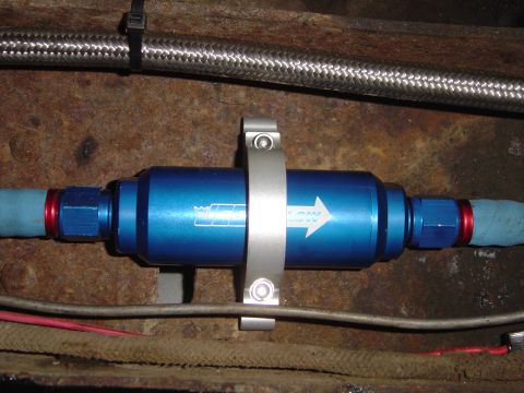 1978 Ford Bronco - Close-up of a blue fuel filter with an arrow indicating flow direction, mounted with a metal clamp.