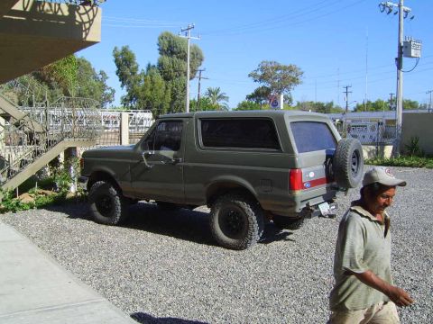 1990 Ford Bronco - This 1990 Ford Bronco is parked outdoors on a gravel lot with a spare tire on the back.