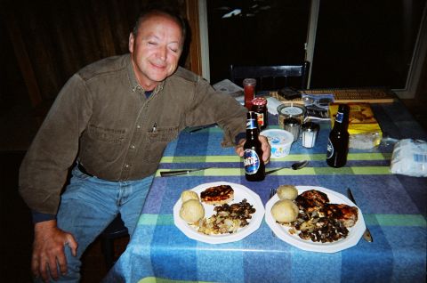 1984 Ford Bronco - A man sits at a table laden with plates of food and bottles of beer, appearing to enjoy a meal.