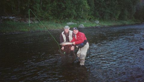1984 Ford Bronco - Two men enjoy a day of fishing in a river, holding up their catch.