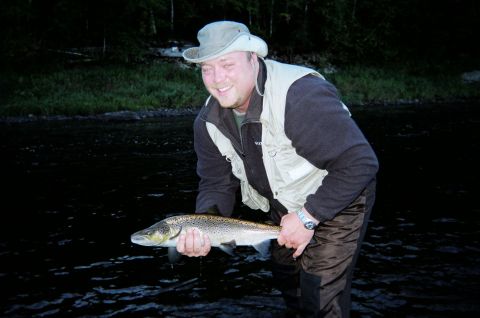 1984 Ford Bronco - A man proudly displays a freshly caught salmon while standing in a river.