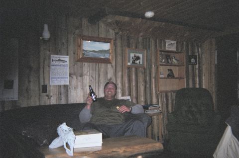 1984 Ford Bronco - A man relaxes in a rustic room, holding a beer and a snack.