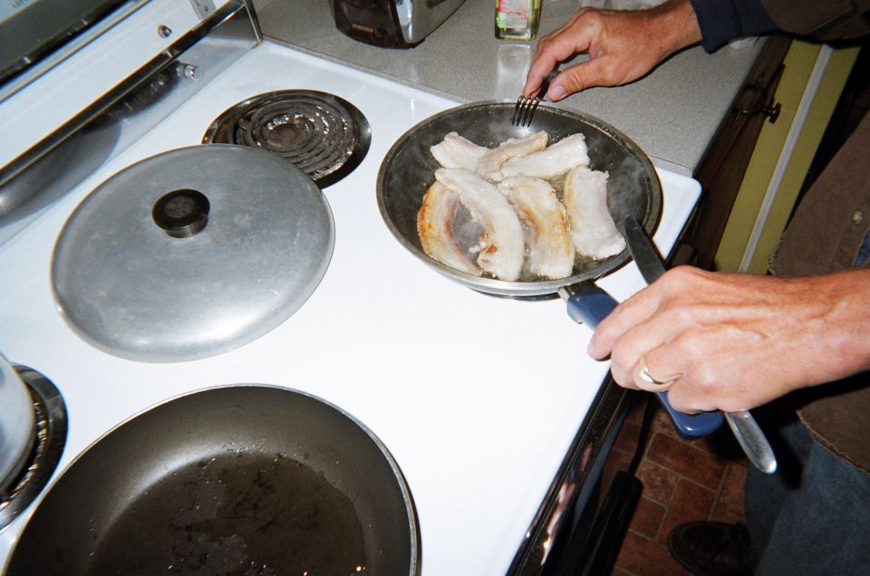Hands cooking bacon in a pan on a white stove