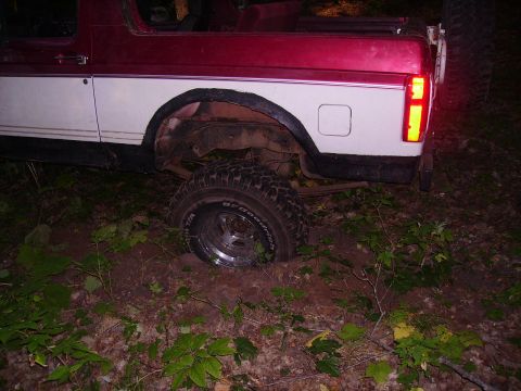 2000 Chevrolet Tahoe - This red and white SUV appears to be stuck in the mud, with its rear wheel partially submerged.