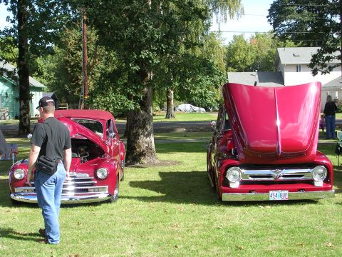 1996 Ford Probe - Two classic red pickup trucks are displayed on a grassy lawn with their hoods open.
