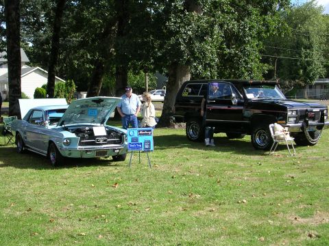1996 Ford Probe - Two vehicles, a classic Ford Mustang and a GMC SUV, are displayed on a grassy field under trees.
