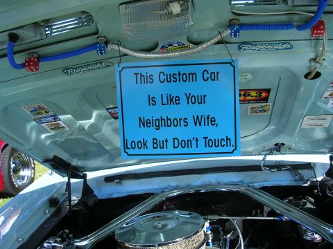 1996 Ford Probe - Custom car engine bay displayed with a humorous sign at a car show.
