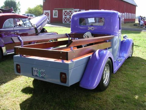 1996 Ford Probe - A custom purple pickup truck with a wooden bed is displayed at an outdoor event, with another vintage vehicle nearby.