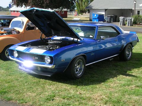1996 Ford Probe - A blue 1969 Chevrolet Camaro Z/28 is displayed with its hood open, parked on a grassy area next to another vehicle.