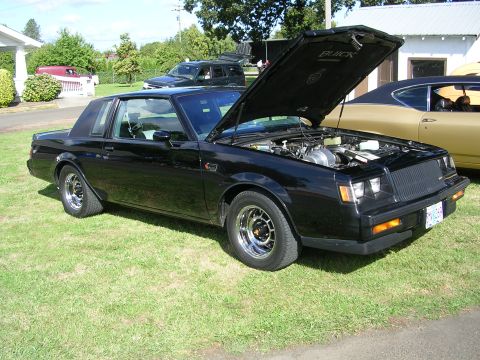 1996 Ford Probe - Black 1987 Buick Grand National at a car show, hood open showing the engine bay.