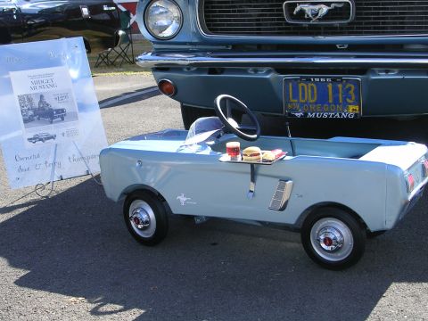 1996 Ford Probe - A pedal car styled as a 1960s Mustang sits before a real 1966 Ford Mustang, complete with a license plate and a tray of food on the pedal c…