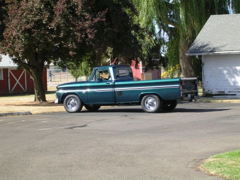 1996 Ford Probe - A classic green pickup truck is parked in a lot next to a building and trees.