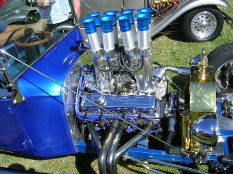 1996 Ford Probe - A custom hot rod with a powerful chrome engine and eight intake stacks is displayed at a car show.