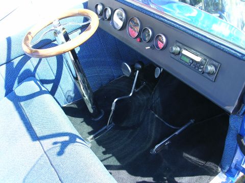 1996 Ford Probe - The interior of a classic car features a wooden steering wheel, blue textured seats, and a dashboard with multiple gauges and a radio.